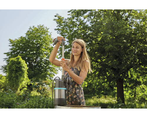 Une femme installe une pompe de récupération d''eau de pluie dans le jardin.
