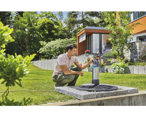Mann bedient eine Gardena Gartenpumpe im Garten