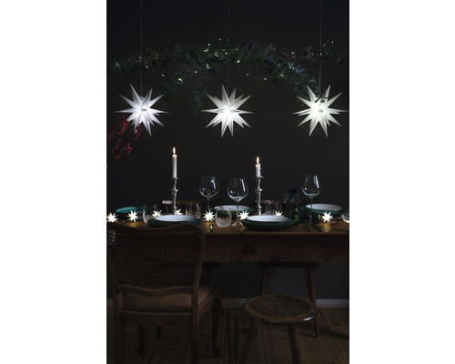 Festlich gedeckter Tisch mit Sternenlichtern, Kerzen und Weingläsern für eine elegante Atmosphäre