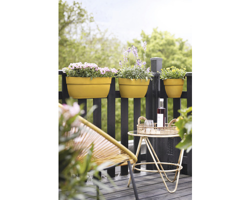 Szene mit Balkonkästen auf einem Geländer, einem Beistelltisch mit Getränken und einem Stuhl.