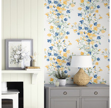Intérieur décoratif avec papier peint à motifs floraux, commode, lampe et cheminée.