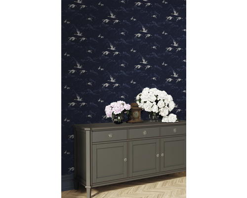 Szene mit Tapete mit Vogelmuster, Kommode, Blumen und Uhr.