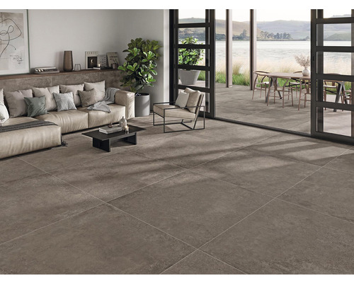 Salon avec carrelage au sol, canapé, fauteuil et vue sur l''espace extérieur avec terrasse