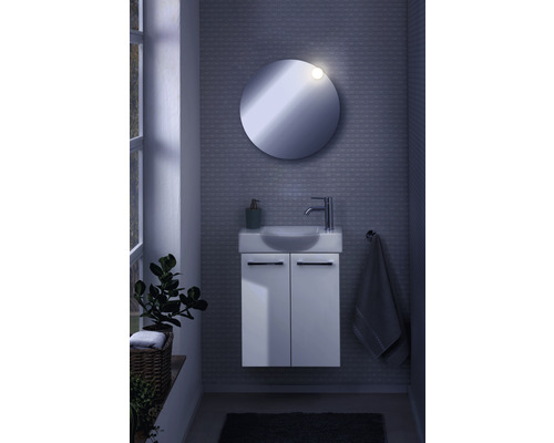 Salle de bains avec miroir rond, meuble sous-lavabo, robinet et porte-serviettes