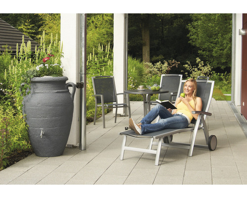 Szene im Garten mit Regentonne in Amphorenform, Gartenmöbeln und entspannter Frau