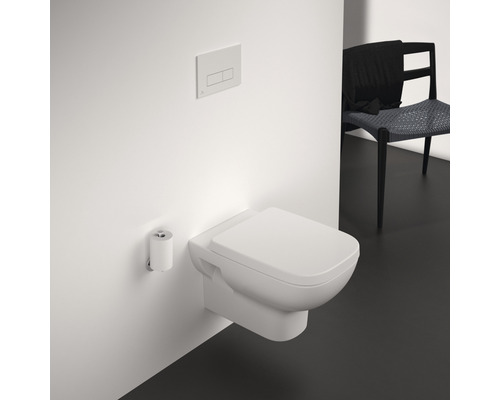 Wandhängendes WC mit Betätigungsplatte und Toilettenpapierhalter in einem Badezimmer.