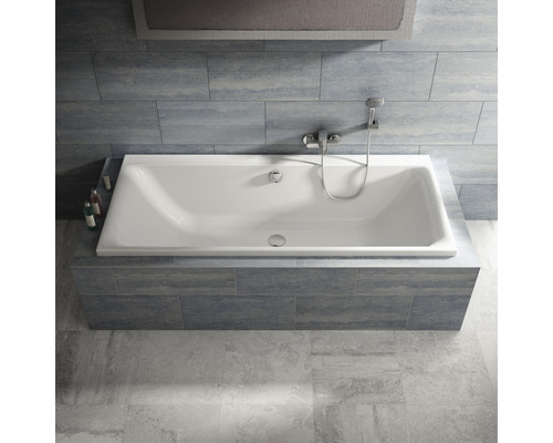 Baignoire rectangulaire avec robinetterie et pommeau de douche dans une salle de bains carrelée