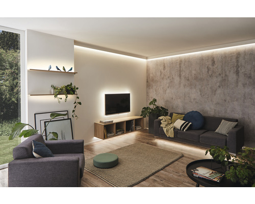 Wohnzimmer mit Sofa, Sessel, Couchtisch, Teppich und Regalen mit indirekter Beleuchtung