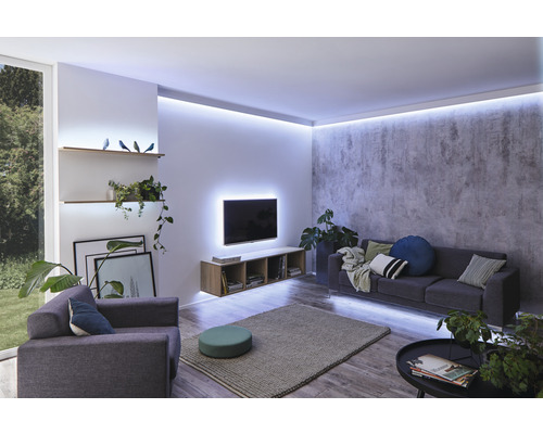 Wohnzimmer mit Sofa, Sessel, Fernseher und indirekter Beleuchtung.