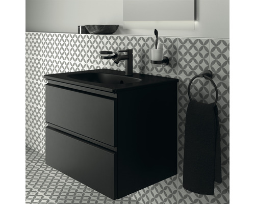 Schwarzer Waschtisch mit zwei Schubladen, Armatur, Seifenspender, Zahnputzbecher und Handtuchhalter vor gemusterter Wand