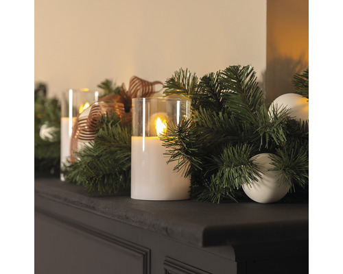 Arrangement décoratif avec bougies LED, verdure de sapin et ornements sur une étagère.