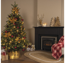 Festlich dekorierter Weihnachtsbaum neben einem Kamin mit Dekorationen und Geschenken