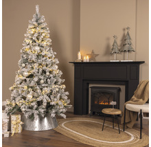 Festlich geschmückter Weihnachtsbaum mit Beleuchtung, Baumschmuck und Weihnachtsgeschenken neben einem Kamin