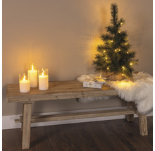 Scène décorative avec banc, bougies, petit sapin de Noël, cadeau et tapis en peau de mouton pour une ambiance festive