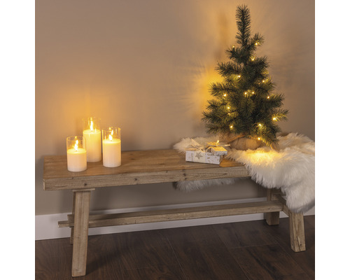 Scène décorative avec banc, bougies, petit sapin de Noël, cadeau et tapis en peau de mouton pour une ambiance festive
