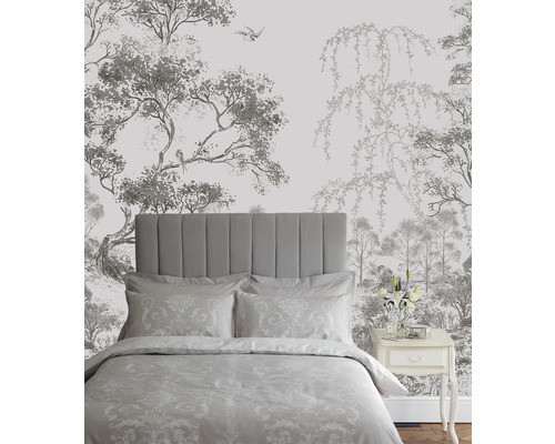 Schlafzimmer mit Bett vor einer Tapete mit Baum- und Vogelmotiven.