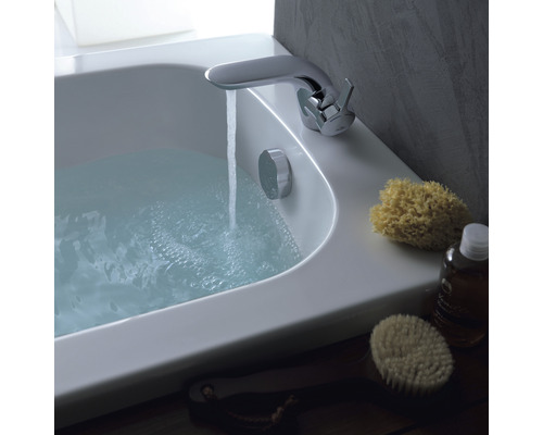 Badezimmerszene mit gefüllter Badewanne, Armatur und Badeutensilien