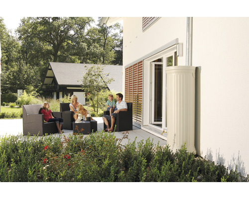 Une famille est assise sur la terrasse avec des meubles de jardin à côté d''une cuve de récupération d''eau de pluie.