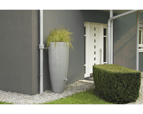 Récupérateur d''eau de pluie avec robinet et partie supérieure plantée à côté d''une maison