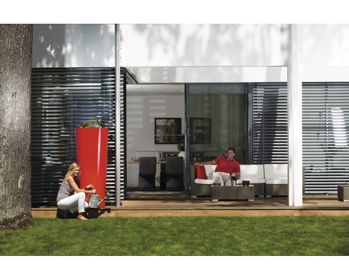 Scène avec un grand réservoir d''eau de pluie, une femme avec un arrosoir et un homme sur un canapé de terrasse