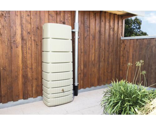 Regenwassertank aus Kunststoff neben einem Fallrohr an einer Holzwand