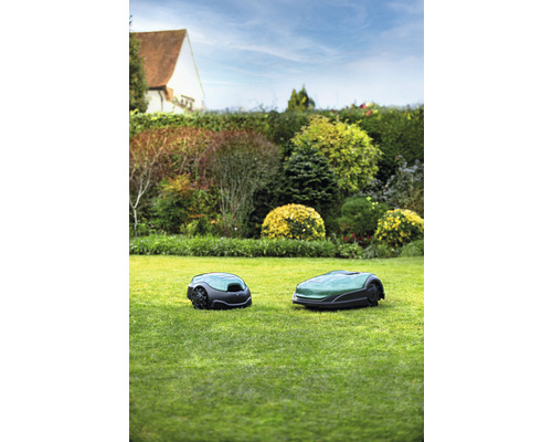 Zwei Rasenmähroboter auf einer Rasenfläche im Garten.