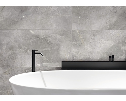 Salle de bains avec carrelage gris aspect marbre, baignoire îlot et robinetterie