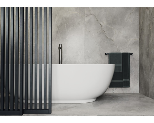 Salle de bains avec baignoire îlot, robinetterie, serviettes et séparateur de pièce