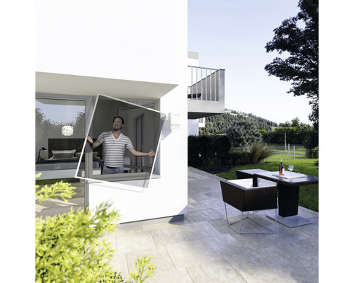 Un homme installe une moustiquaire à la fenêtre d''une maison moderne avec terrasse