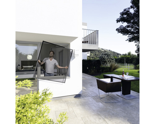 Un homme installe une moustiquaire à la fenêtre d''une maison avec terrasse