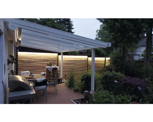 Terrasse avec auvent, table, chaises et éclairage.