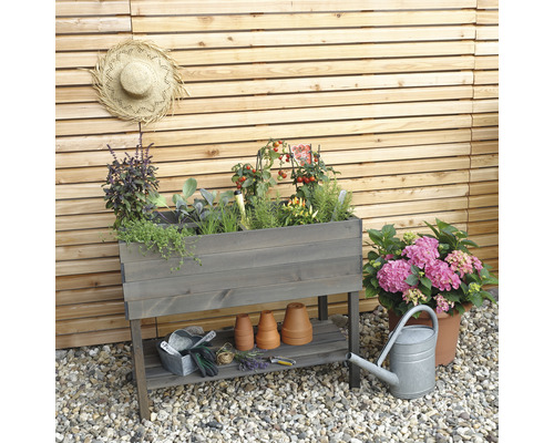 Jardinière sur pieds en bois avec herbes aromatiques, tomates et outils de jardin