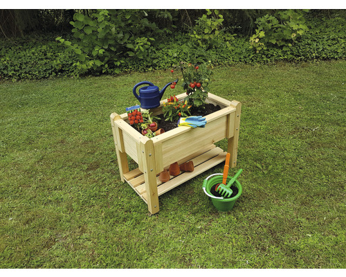 Hochbeet aus Holz mit Pflanzen und Gartenzubehör im Garten