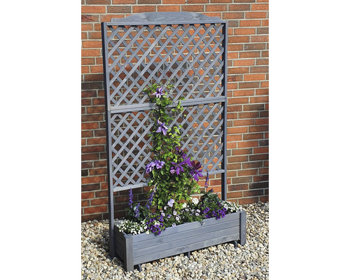 Holz-Pflanzkasten mit Rankgitter und Bepflanzung vor einer Ziegelwand