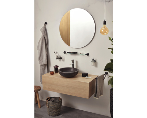 Modernes Badezimmer mit Waschtisch, rundem Spiegel und stilvollen Accessoires.