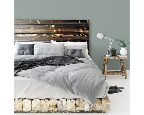 Schlafzimmer mit Holzbett, Nachttischlampe und Dekorationen für eine helle und entspannte Atmosphäre.