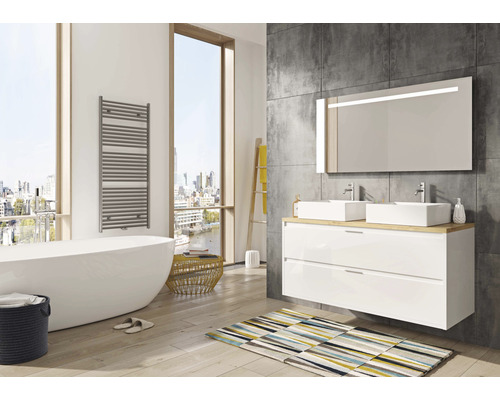 Salle de bain moderne avec baignoire, meuble-lavabo, miroir et sèche-serviettes.