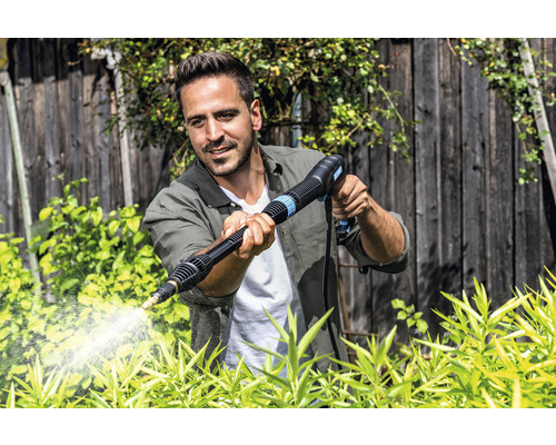 Un homme utilise un nettoyeur haute pression dans le jardin pour nettoyer les plantes