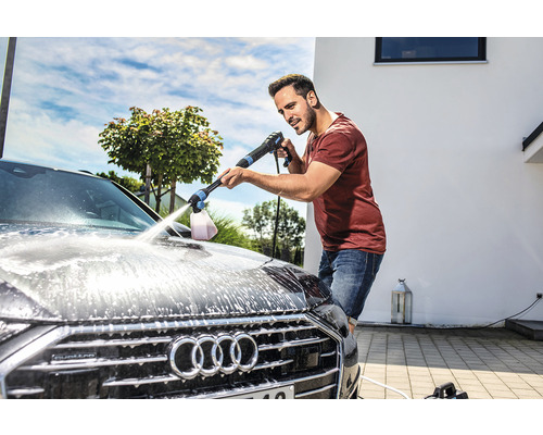 Mann reinigt Auto mit Hochdruckreiniger und Schaumdüse