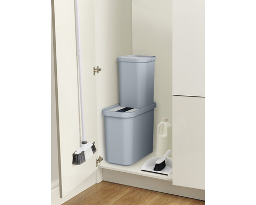 Des poubelles, un balai et une pelle à poussière sont rangés proprement dans le placard