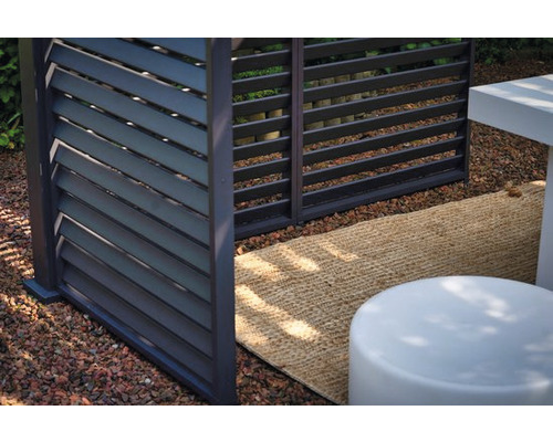 Detailansicht eines modernen Sichtschutzzauns mit horizontalen Lamellen in einem Gartenbereich.