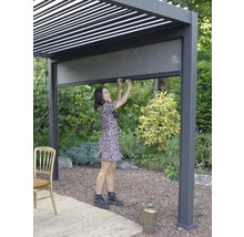 Femme actionnant un store latéral sur un toit de terrasse dans le jardin.