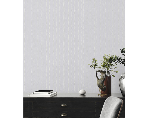 Szene mit Mustertapete, Kommode, Dekoration und Pflanze.