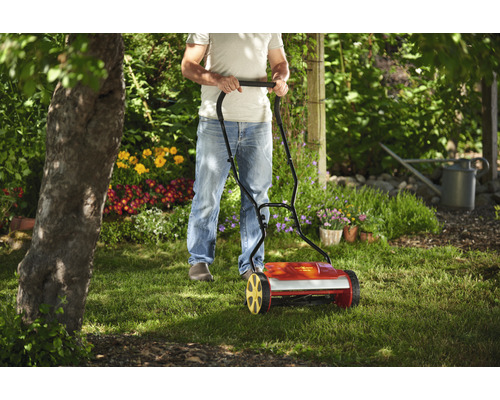 Un homme utilise une tondeuse à gazon hélicoïdale dans le jardin