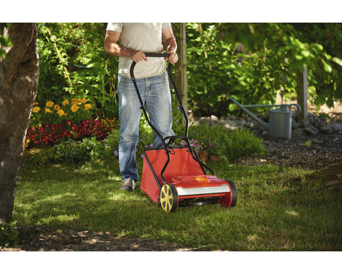 Une personne utilise un scarificateur dans le jardin.