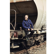Homme avec une veste à carreaux et des chaussures de travail assis sur un wagon de marchandises