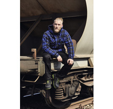 Homme avec une veste à carreaux, un pantalon et des chaussures de travail assis sur un wagon de marchandises