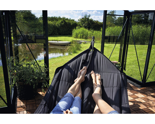 Des personnes se détendent dans un hamac dans une serre donnant sur un lac