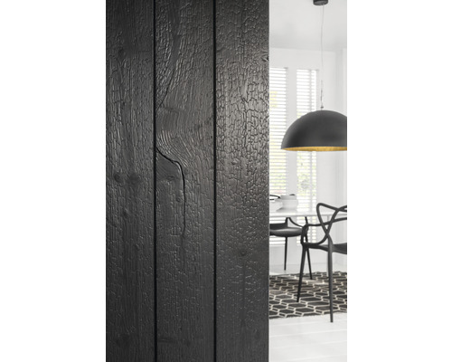 Mur en bois noir à côté de la salle à manger avec table, chaises et lampe