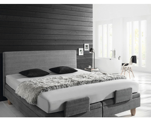 Chambre avec lit boxspring, lampe de chevet et baignoire en arrière-plan